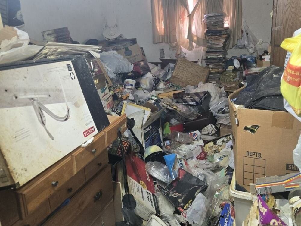 Before: a bedroom filled floor to ceiling with boxes, papers and household items