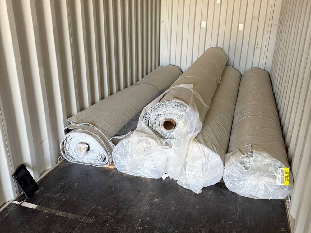 Before: rolls of carpet and padding filling a storage unit