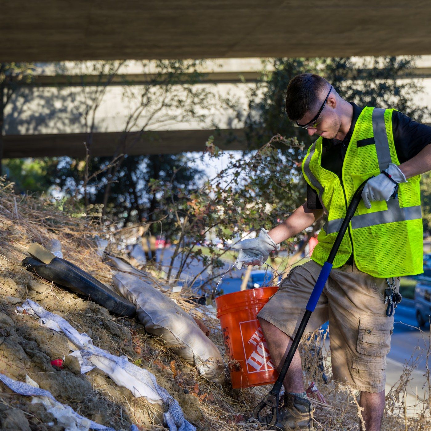 Dump Ninja crew member in a high-visibility vest clearing debris from a roadside embankment