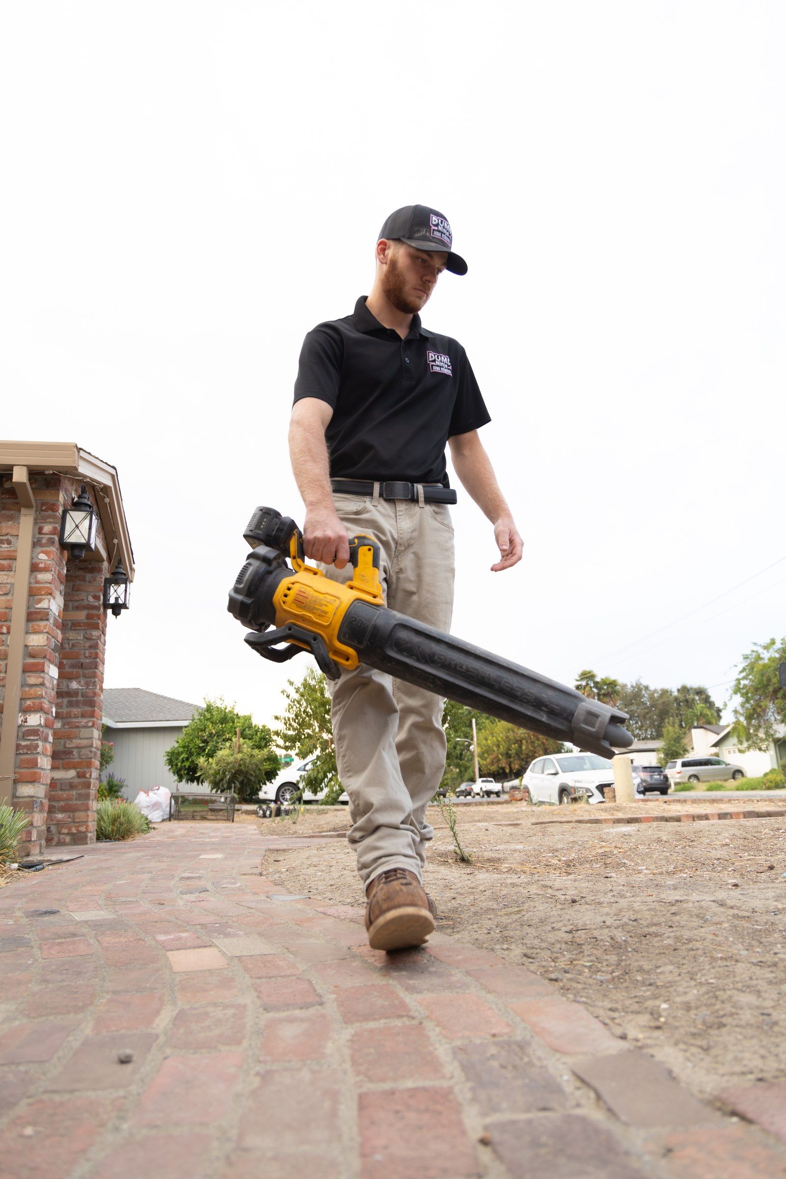 Dump Ninja crew member clearing the driveway with a leaf blower after a Woodland junk removal job