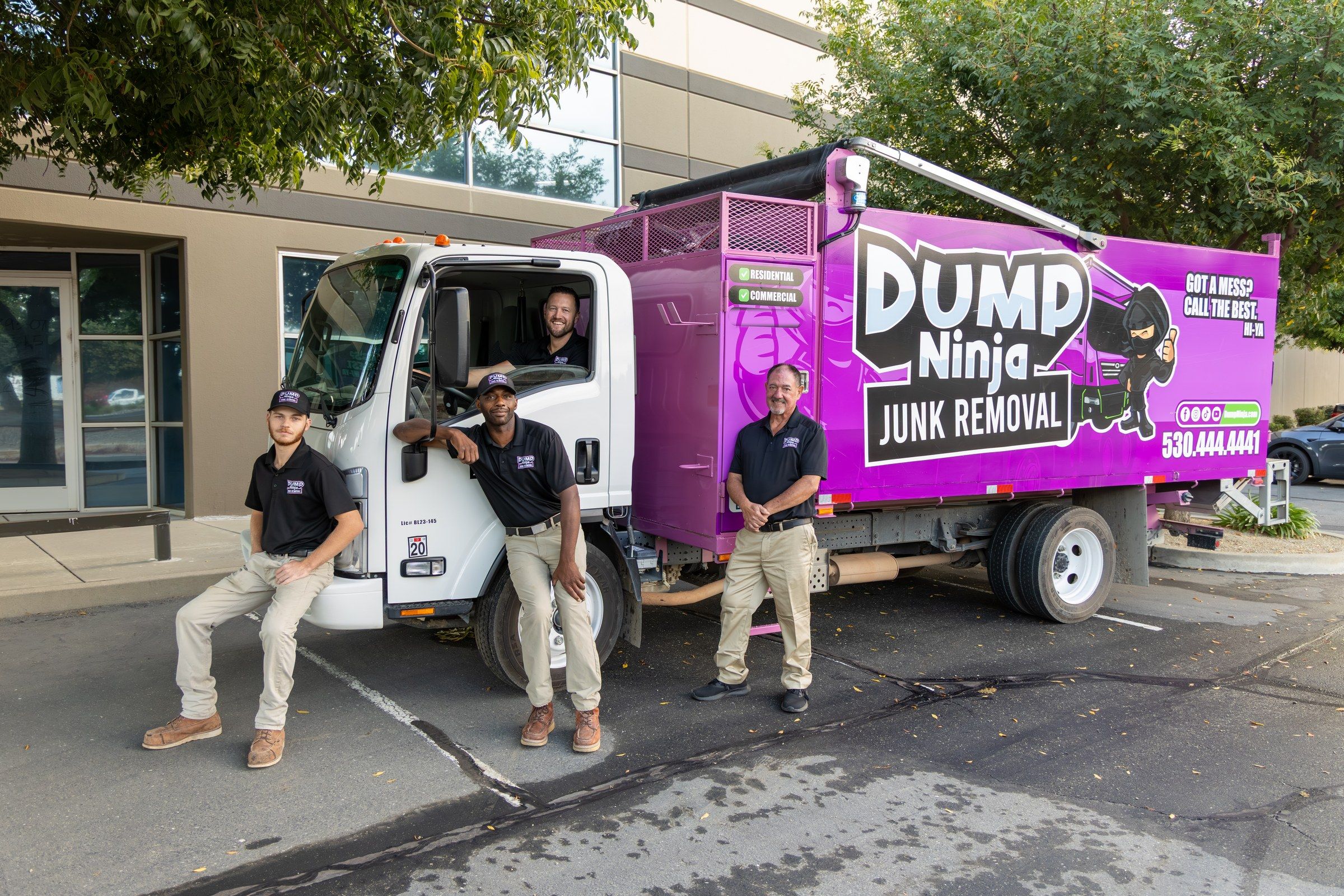 The Dump Ninja crew of four standing with the magenta 21-yard dump truck in Woodland, California
